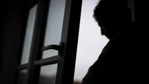 Eine Person steht im Gegenlicht am Fenster