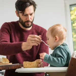 Ein Mann füttert ein Baby mit Brei