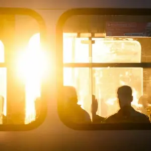 Fahrgäste sitzen bei Sonnenaufgang in einer Stadtbahn