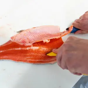 Eine Person schneidet ein Fischfilet