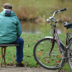 Ein älterer Mann sitzt auf einer Parkbank