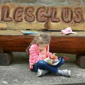 Ein Kind liest vor einer Bank