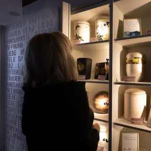 Frau betrachtet Regal mit Urnen