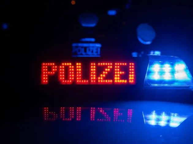 Polizisten vor einem Polizeiauto (Symbolbild)