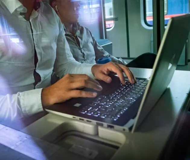 Pendler arbeiten am Laptop im Zug