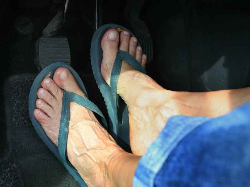 Frau mit Flip Flops am Steuer eines Autos