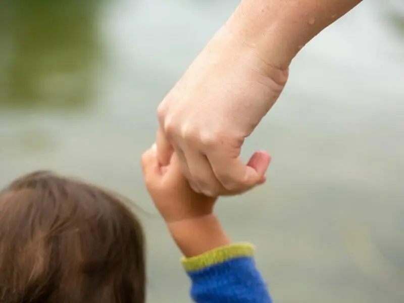 Mutter hält Kind an der Hand