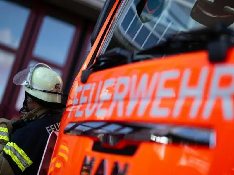 Feuerwehrmann steht neben einem Feuerwehrauto (Symbolbild)