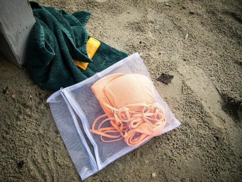 Bikini in einem Wäschenetz am Strand