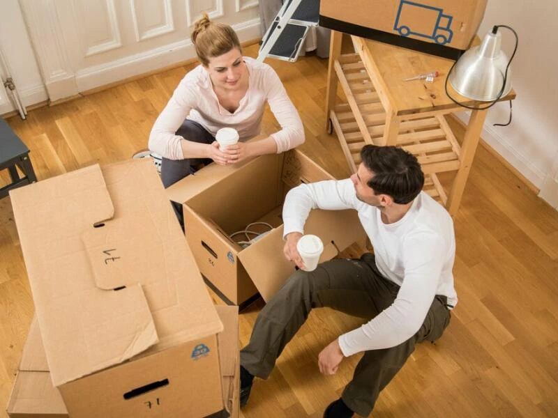 Ein Paar sitzt in einer Wohnung zwischen Umzugskisten