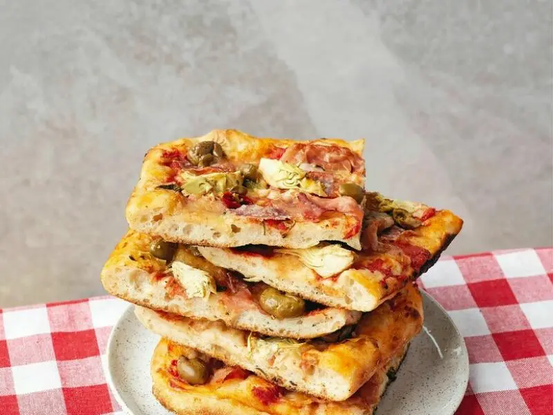Eckige Pizzastücke liegen gestapelt auf einem Teller
