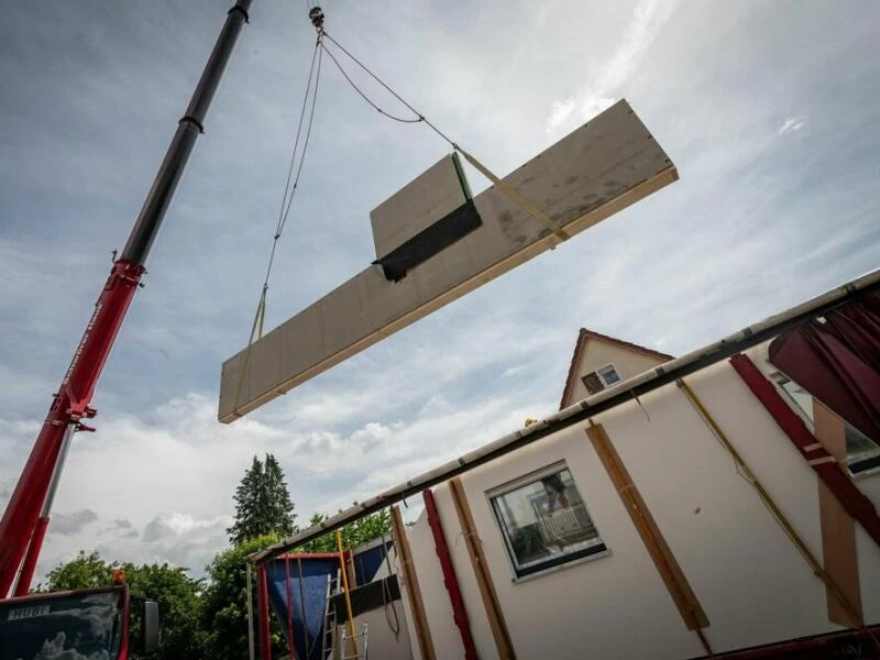 Ein Kran hebt eine vorgefertigte Wand auf einer Baustelle