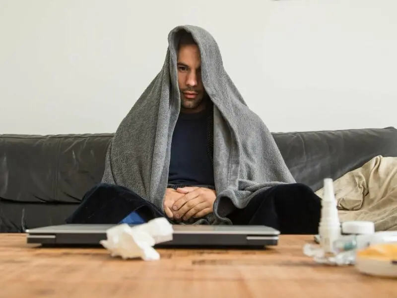 Ein Mann sitzt mit Erkältung auf der Couch