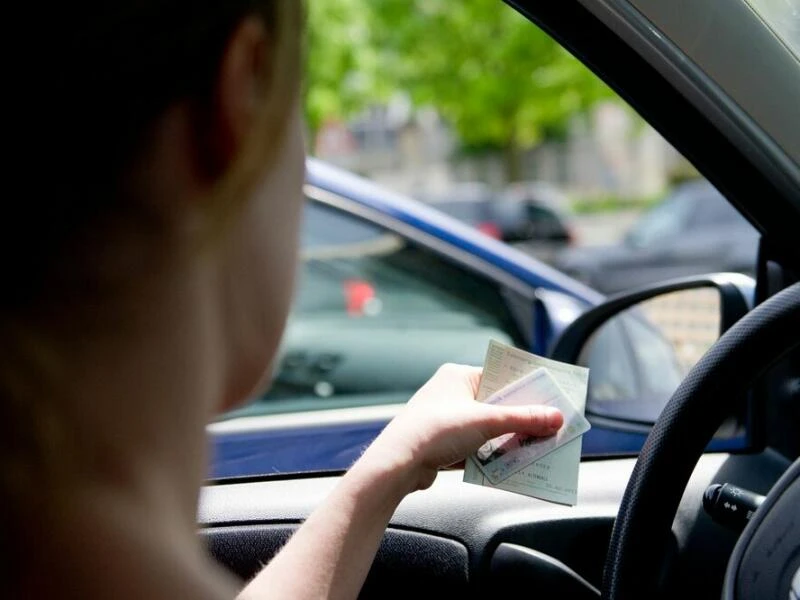 Eine Frau hält Fahrzeugpapiere in der Hand