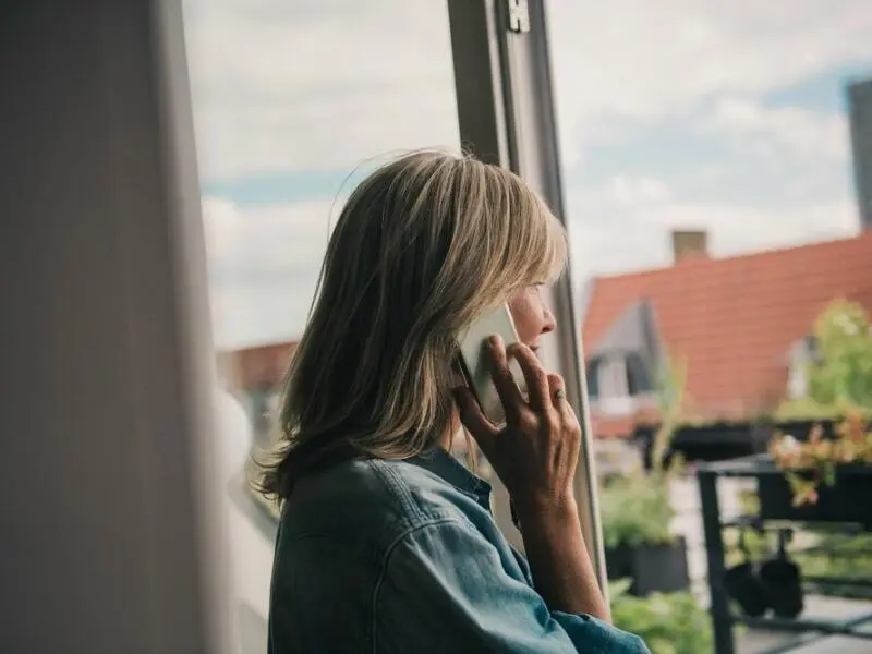 Eine Frau telefoniert am Fenster