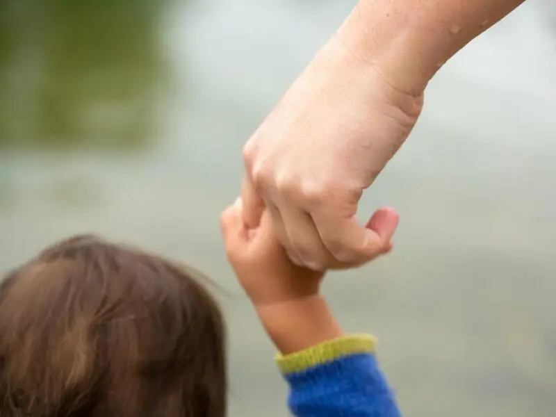 Ein Kind an der Hand einer erwachsenen Person
