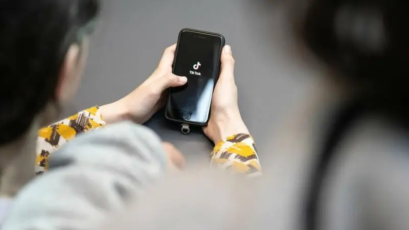 Jugendlicher schaut auf ein Smartphone mit der App von TikTok