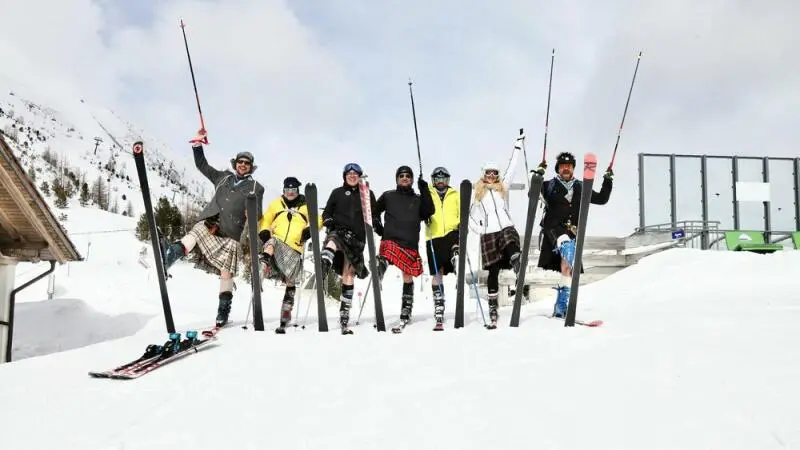 Eine Gruppe Kilt-Träger auf Skiern im Schnee.