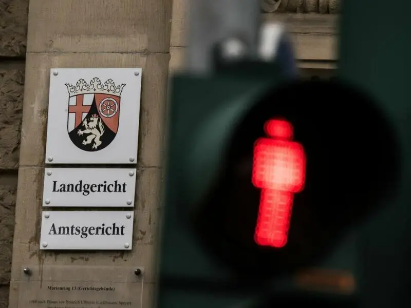 Eine Ampel leuchtet vor dem Hinweisschild am Landgericht Landau