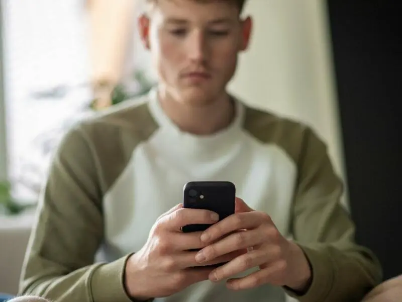 Ein junger Mann tippt auf seinem Handy