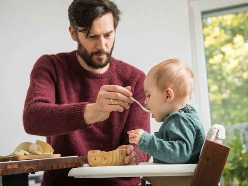 Ein Mann füttert ein Baby mit Brei