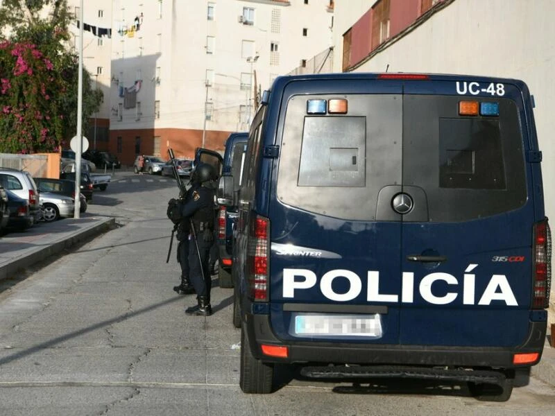 Spanische Polizisten stehen bei einem Einsatzfahrzeug.