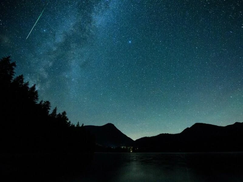 Eine Sternschnuppe leuchtet am Himmel über dem Walchense (Bayern)