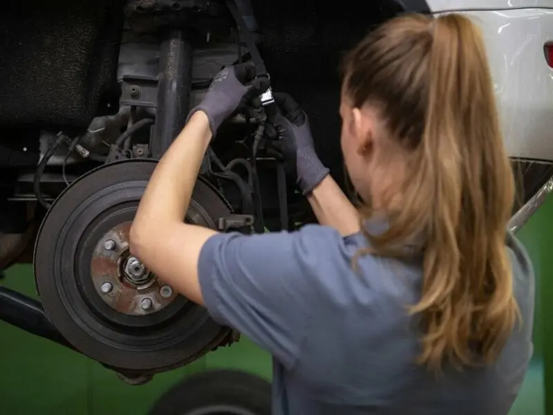 Eine KFZ-Mechanikerin wechselt die Bremsscheiben am Auto