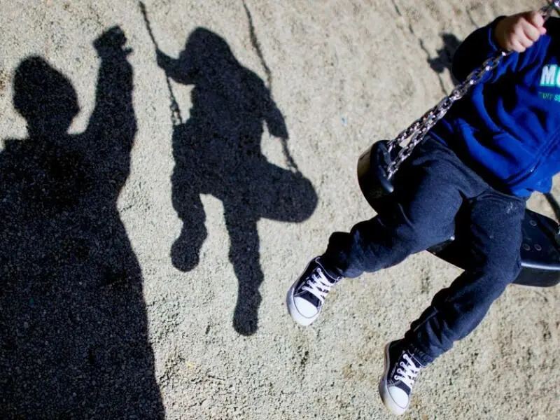 Ein Kind auf einer Schaukel und Schatten