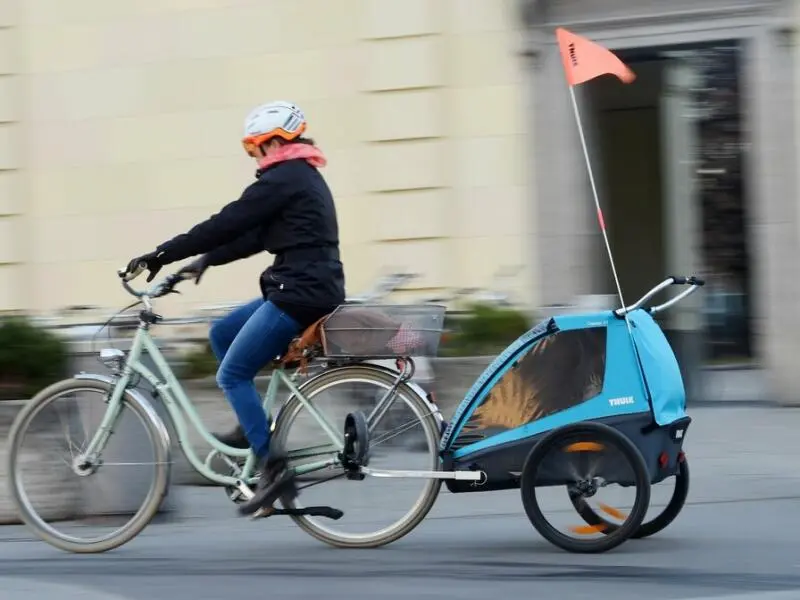 Jemand ist auf einem Fahrrad mit Kinder-Anhänger unterwegs