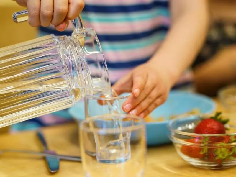 Ein Kita-Kind schenkt sich Wasser ein