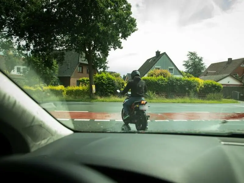 Motorradfahrer biegt links ab auf nasser Straße