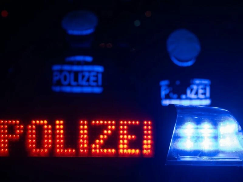 Zwei Polizisten stehen vor einem Streifenwagen