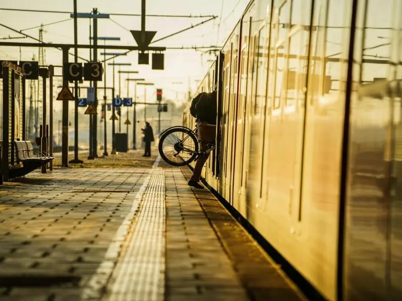 Ein Bahnreisender hebt sein Fahrrad in eine S-Bahn