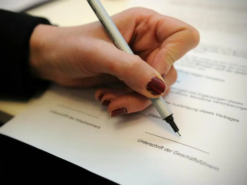 Eine Frau unterschreibt einen Arbeitsvertrag