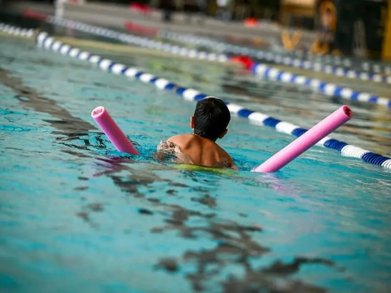 Kind mit Schwimmnudel im Sportbecken