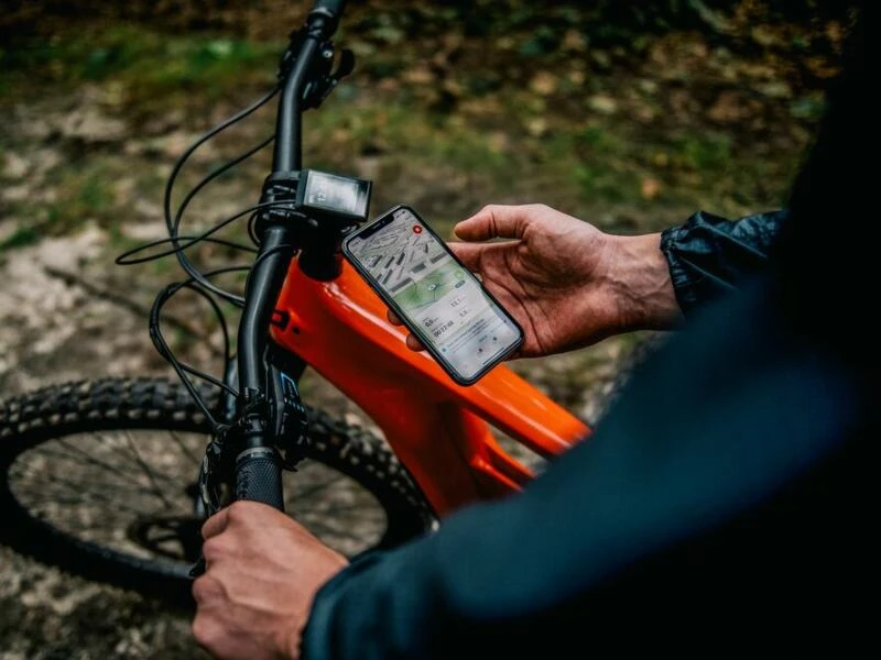 Ein Mann öffnet eine App für sein E-Mountainbike