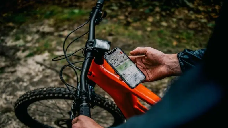 Ein Mann öffnet eine App für sein E-Mountainbike