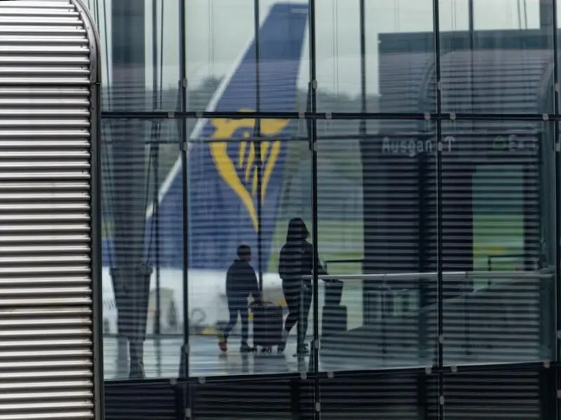 Passagiere vor dem Leitwerk einer Ryanair Maschine