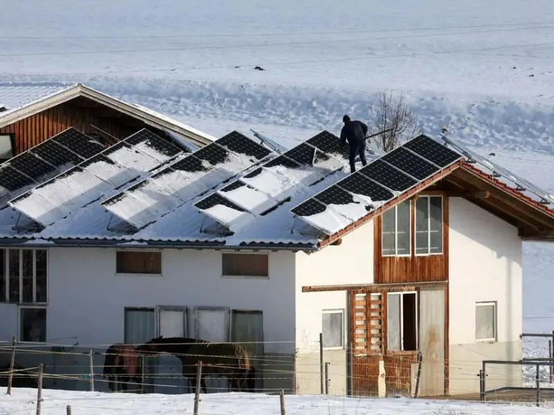 Mann befreit Photovoltaikdach vom Schnee