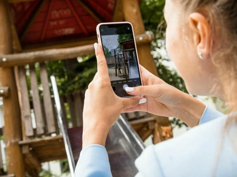 Eine Mutter fotografiert ihr Kind auf einem Spielplatz