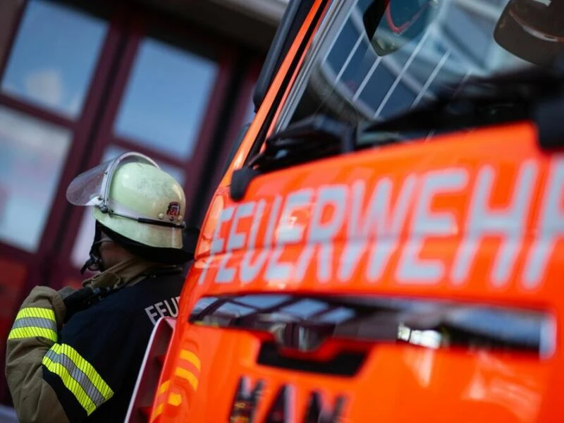 Feuerwehrmann steht neben einem Feuerwehrauto.