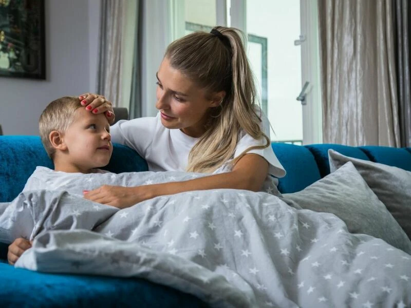 Eine Mutter fasst ihrem Sohn prüfend an die Stirn