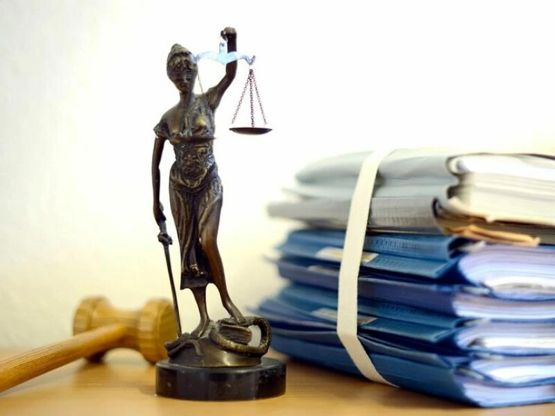 Eine Statuette der Justitia vor einem Aktenstapel