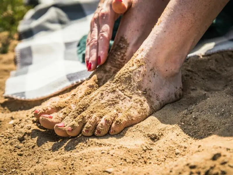 Sandige Frauenfüße am Badesee