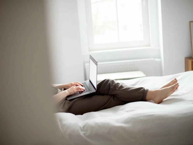 Eine Frau sitzt mit Laptop im Bett