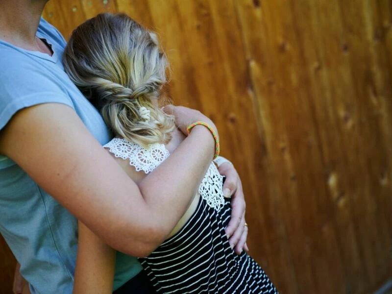 Ein Mädchen wird von seiner Mutter in den Arm genommen