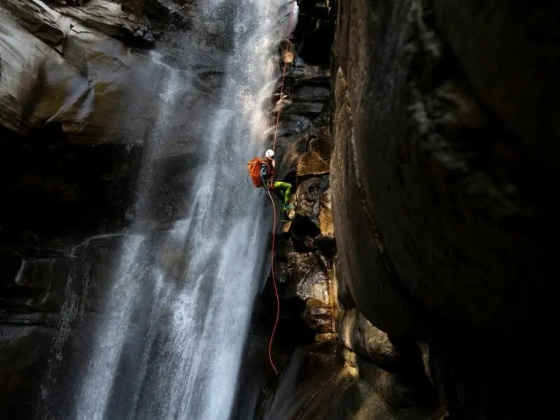 Ein Canyoning-Sportler klettert einen Wasserfall hoch.