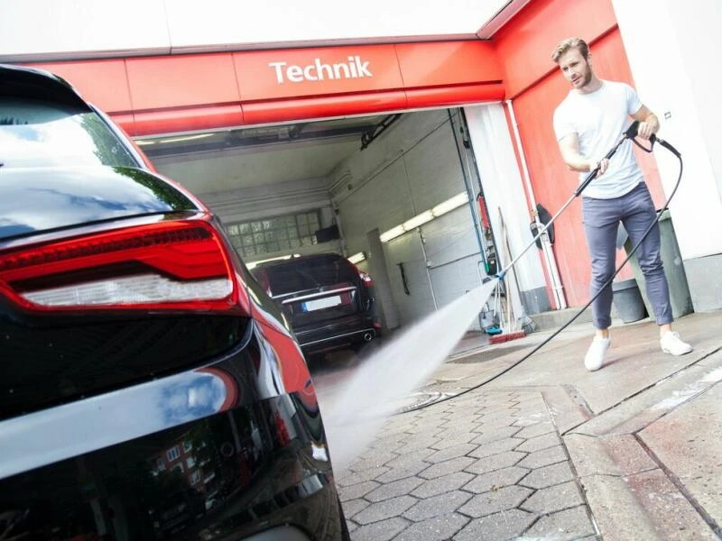 Ein Mann wäscht an einer Tankstelle sein Auto