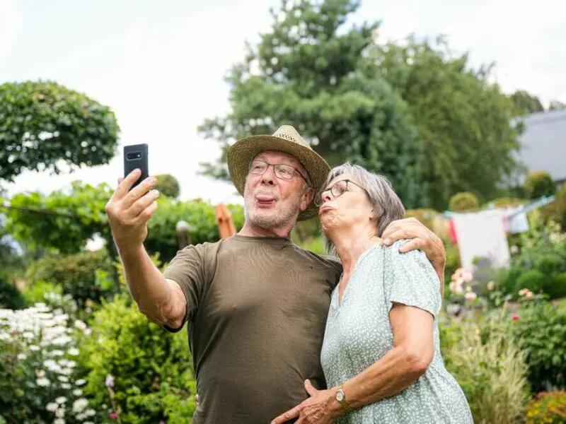 Zwei ältere Menschen nehmen im Garten ein Selfie auf